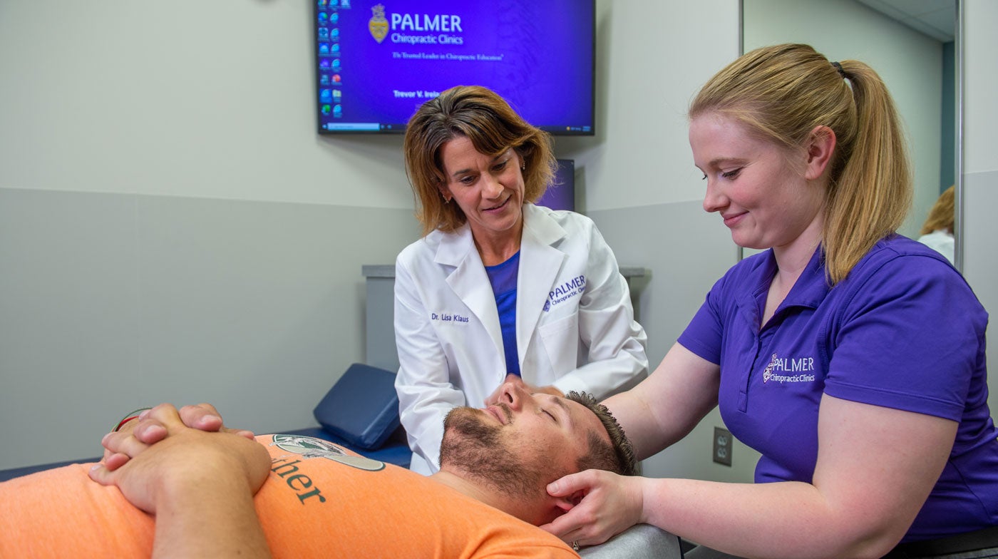 Dr. Klaus overseeing clinic intern palpating patient's neck.