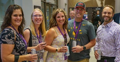 Five people smiling with drinks in hand.