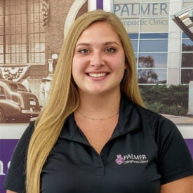 Intern of the Month Valerie Moldovan smiling in front of Clinic wall.