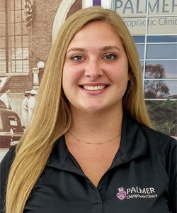 Intern of the Month Valerie Moldovan smiling in front of Clinic wall.