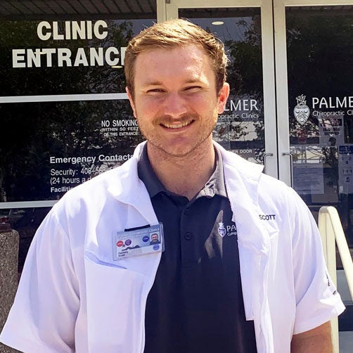 Palmer student in white clinic coat outside Palmer Clinic.