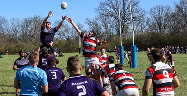 Two teams of men's rugby players running on pitch.