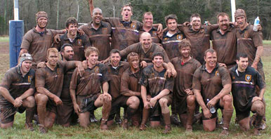 Group photo of 1992 Palmer Men's Rugby team covered in mud.
