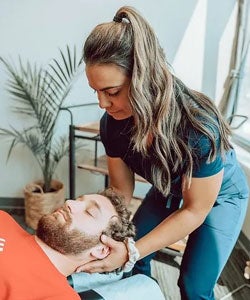 Dr. Leilani Zinsli palpating patient's neck.