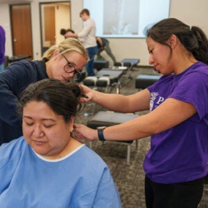 Two students review patient's neck in technique classroom.