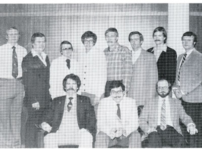 Group of chiropractors in formal clothing in black and white historical photo.