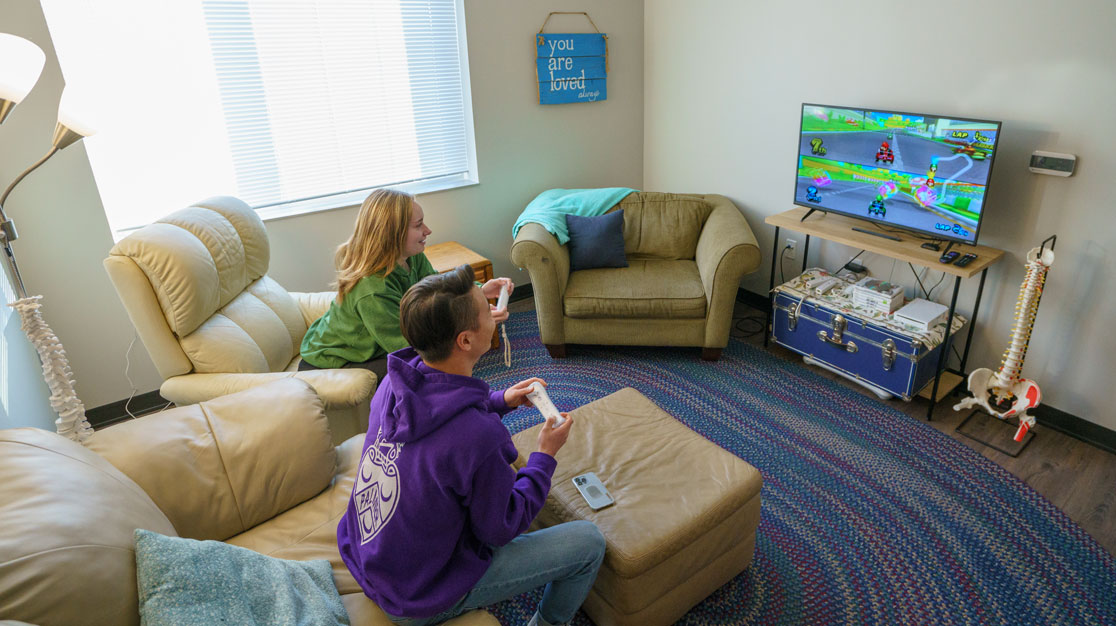 Two students playing video games in VanDuyne Hall living room.