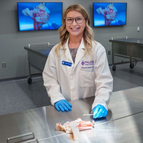 Megan Beveridge in lab coat with anatomy specimen.