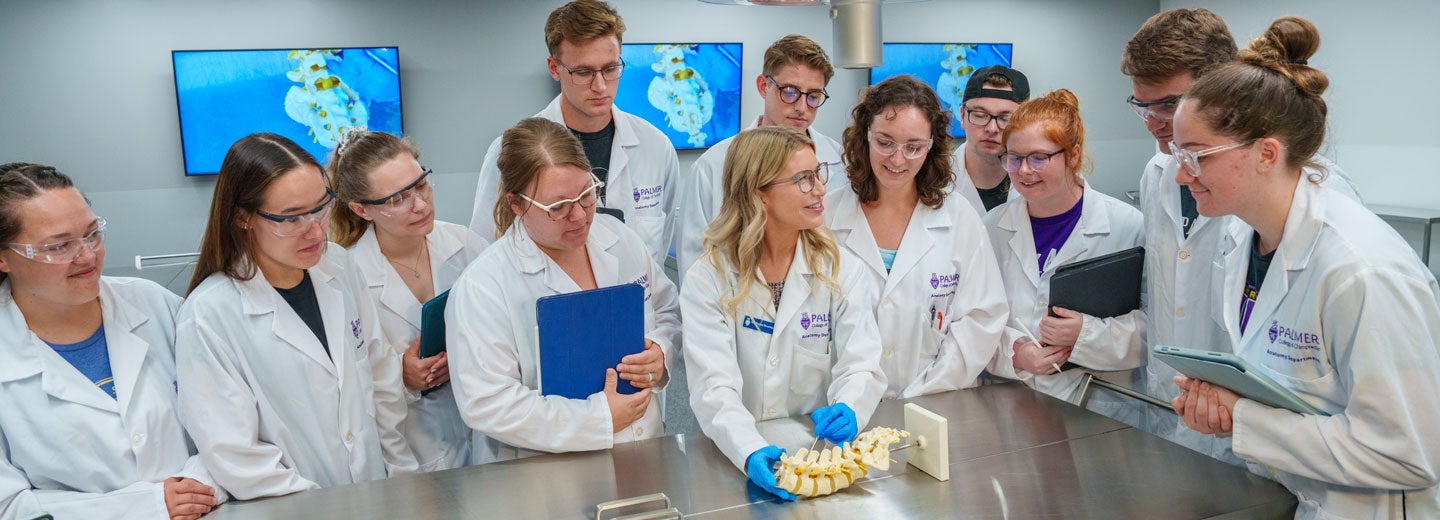 Instructor in wet lab with several students in lab coats.