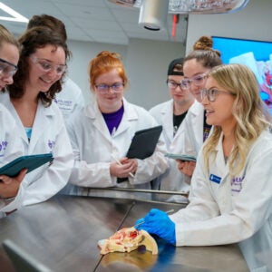 Instructor in wet lab with several students in lab coats.