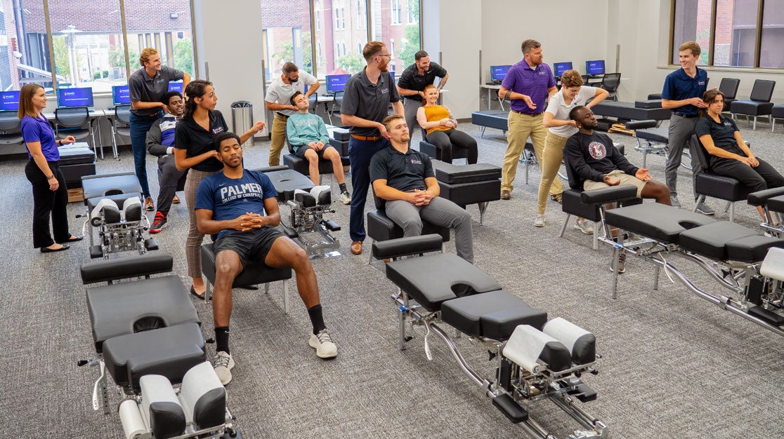 Large room of students practicing neck palpation on patients.