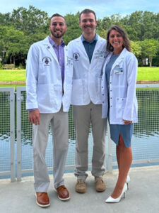 Three Palmer Florida students outdoors in white clinic coats.