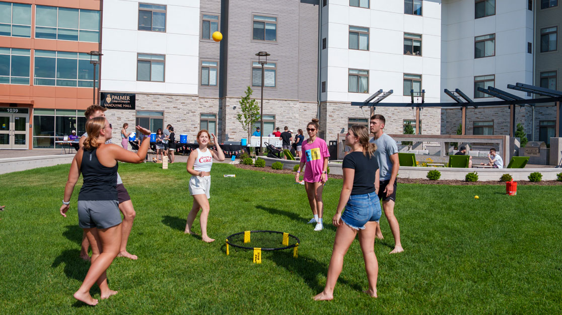 Group of students play ball game on lawn outside of VanDuyne Hall on Main Campus.