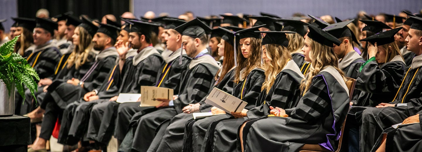 Large room of students in graduation caps and gowns.