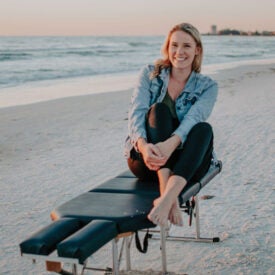 Dr. Sandy Spines sitting on adjusting table on beach.