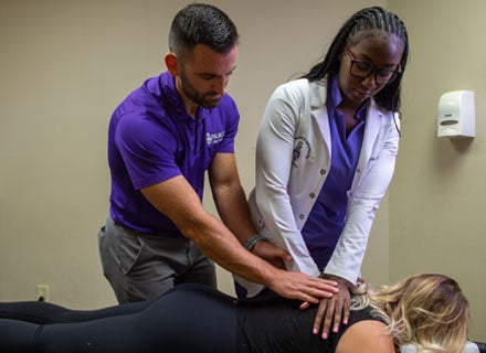 Clinic student and instructor adjusting patient's upper back.