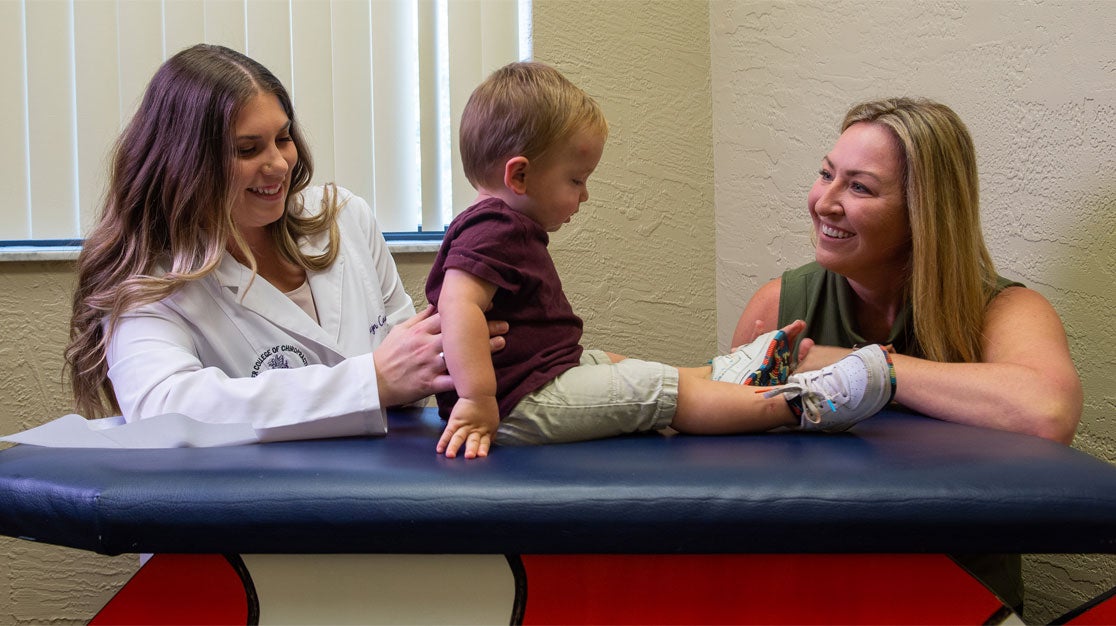 Instructor and student evaluating child on table.