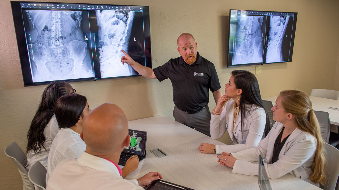 Instructor reviewing large screen X-ray with table of students.