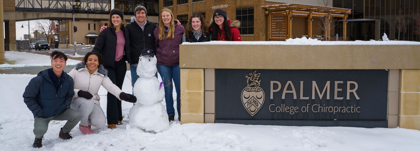 Group of students posing with snowman.