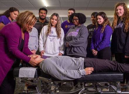 Group of students watching instructor palpate patient's neck.