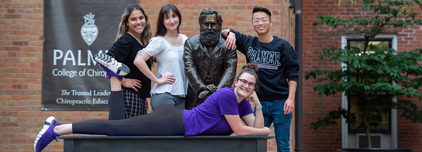 Group of students posing with First Adjustment Statue.