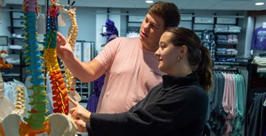 Two students looking at spine model in the Campus Store.