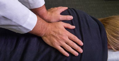 Chiropractor's hands on patient's back.