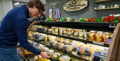 Student picking out pre packaged salad from Dave's Coffee Corner.
