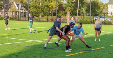 Students playing flag football in outdoor field.