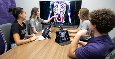 Group of students on iPads reviewing digital skeletal model.