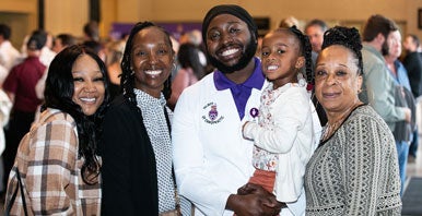 Family photo with student in white coat.