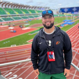 Student Vinny Williams standing in front of outdoor field.