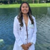 Cindy Le in white chiropractic coat in front of fountain.