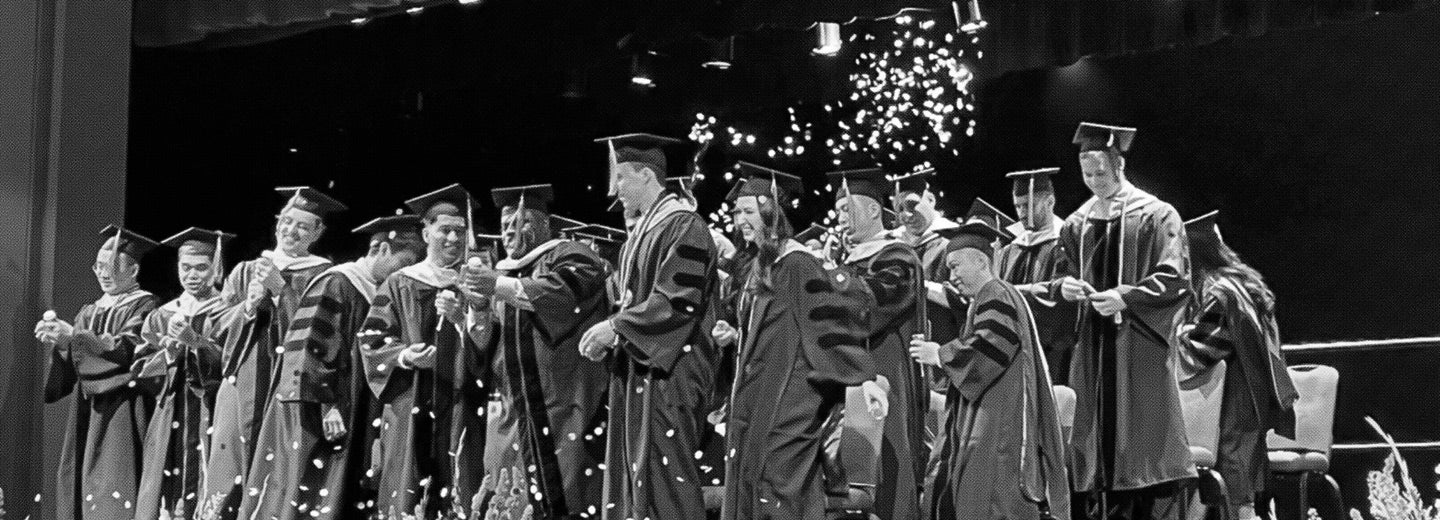 West Campus graduates throwing cards into the air.