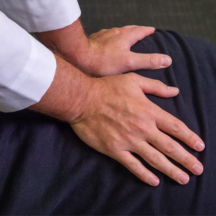 Hands adjusting patient's back.