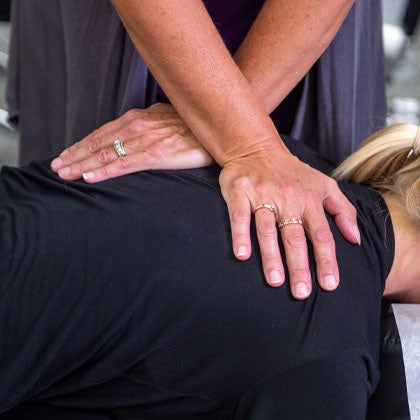 Hands adjusting patient's shoulder.