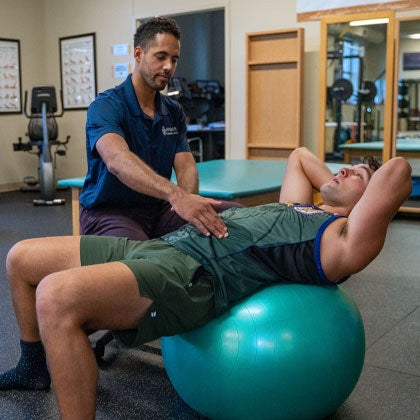 Rehab clinician working with patient on giant ball.