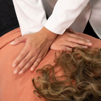 Hands adjusting patient's back.
