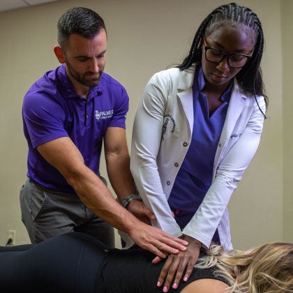 Clinician helping student with patient adjustment.