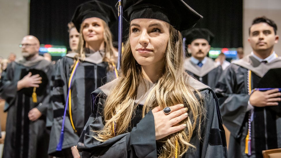 Students standing for pledge during graduation.