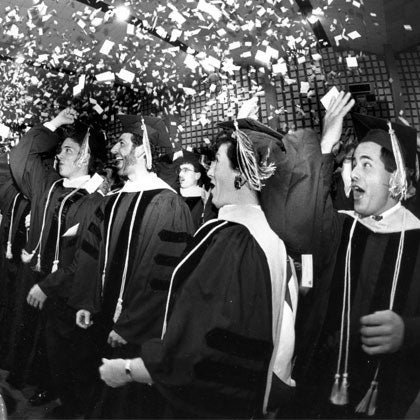 Historical photo of graduates tossing cards in the air.