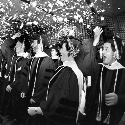 Historical photo of graduates tossing cards in the air.