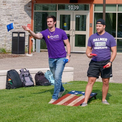 Students playing bags in front of Vanduyne Hall.