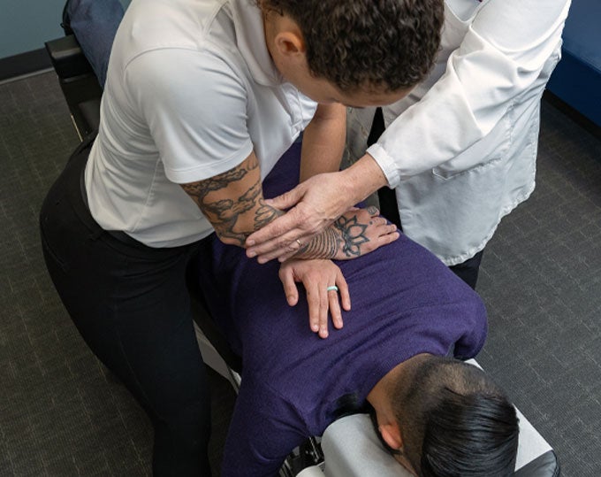 Clinician and intern adjusting patient's back.