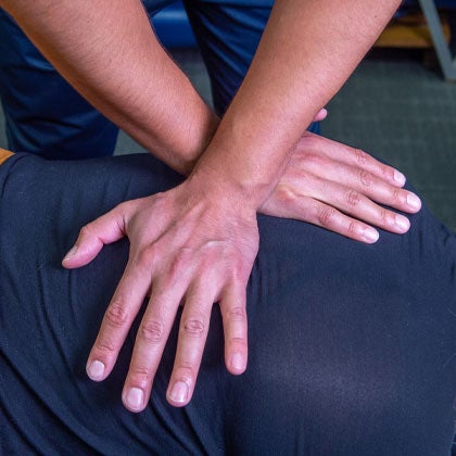 Crossed hands on patient's back.