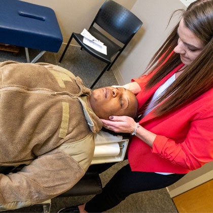 Clinician palpating neck of military member.