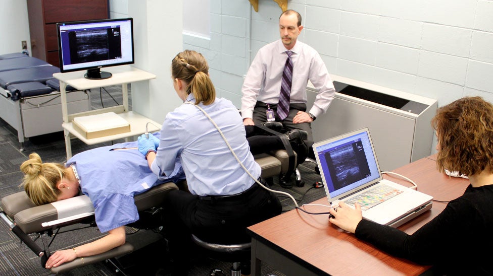 Research clinicians doing ultrasound on patient's back.