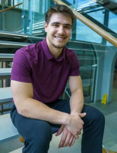 Andrew Wanke sits on the spine-inspired monumental staircase at Palmer's Main Campus. 