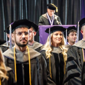 Palmer Florida class 262 group photo in hats and gowns in front of speaker.