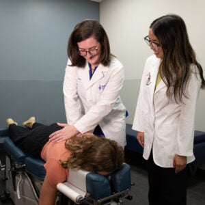 Dr. Forlow sets up to adjust a patient's back while a student intern observes.